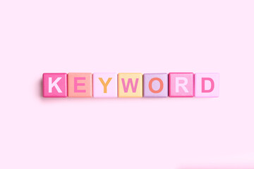 Colorful cubes with word KEYWORD on pink background, flat lay