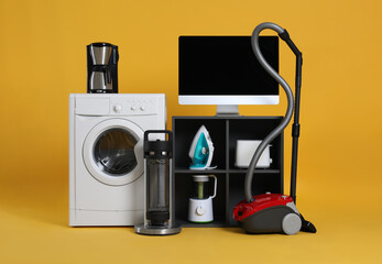 Set of different home appliances with vacuum cleaner on yellow background