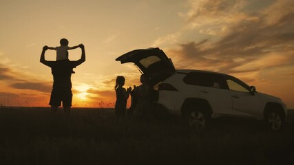 Silhouette the happy family of four people, mother, father and two children are happy sitting in the open trunk of a car at the sunset time. Concept of summer vacation and friendly family. - Powered by Adobe