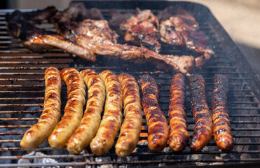 Grilled barbecue sausages and sheep meat on the grill outdoors.