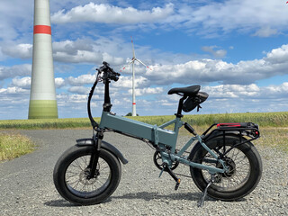 Modern electric Fatbike with wind turbine in the background - 365076455