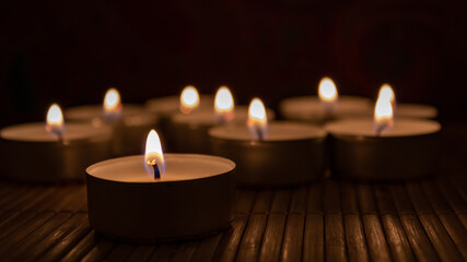 candles on a dark background. Close up and selective focus of tea light with blurred candles in the beackground