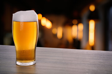 Fresh cold beer on wooden table in pub, space for text