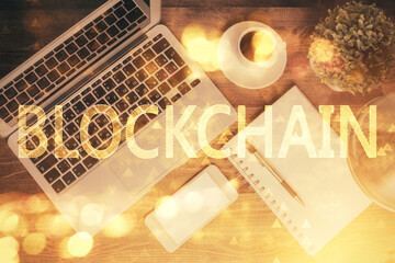 Blockchain theme hologram drawings over computer on the desktop background. Top view. Double exposure.