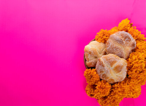 Cempazuchitl flowers and Mexican skull on bright pink background.