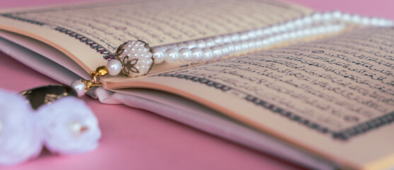 Holy Quran with rosary beads with pink background