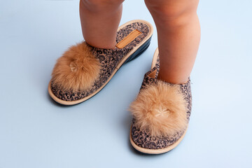 Little legs in mom's slippers. Big shoes on the baby