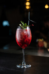 Making cocktails at home like an expert nightclub barman. Fresh and juicy colorful homemade cocktails garnished with berries, orange, mint on dark background.