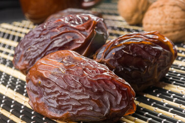 Big luxury dried date fruit on the bamboo mat, kurma ramadan kareem concept, close up.