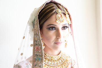 Beautiful female model wearing traditional Sikh wedding attire as she prepares for the ceremony