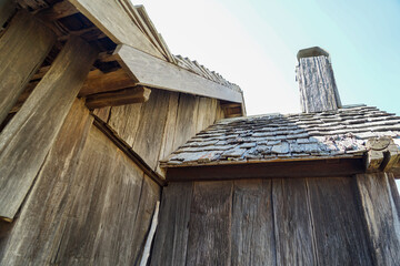 Looking up at walls, shingled roof and chimney of a pioneer built timber slab hut. Queensland, Australia. 
