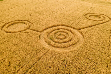 Fake UFO circles on grain crop yellow field, aerial view from drone. Round geometry shape symbols...