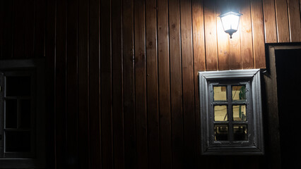 Wooden window with lighted wooden wall lanterns shining light in the dark. Space for text. Texture concept.
