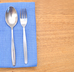 Silverware or flatware set of fork, spoon and knife over kitchen towel. Isolated on wooden board