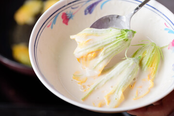 Pumpkin flower dipping in flour preparing to fried in pan, edible flower