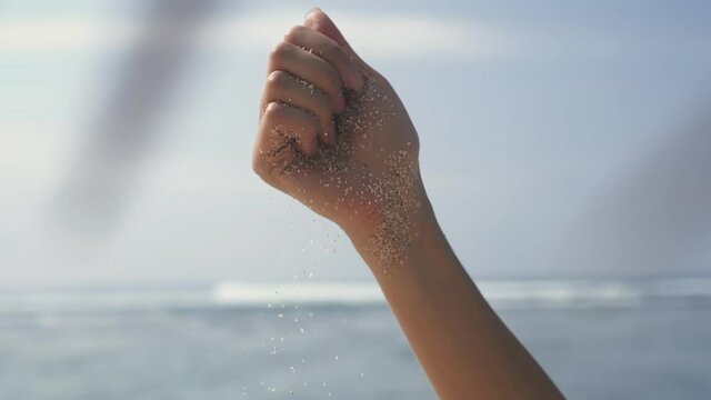 Time is running like sand through your fingers. Time, travel concept. woman hand sifting sand between fingers. unrecognisable lady enjoying paradise island near seaside in Bali, sun shine bright.