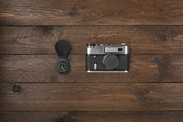 Tourist essentials. Top view of compass and vintage camera on wooden table