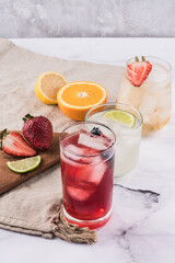 Refrescos y cocteles veraniegos con frutas cortadas como frutillas, limón, naranja, y arándanos. 