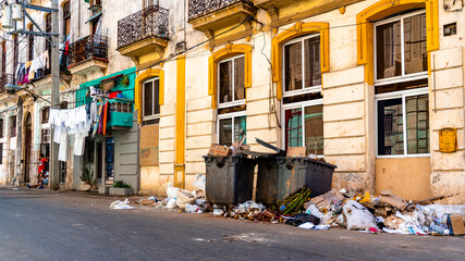 Fototapeta na wymiar Havana, Cuba. Pile of trash next to some fully loaded garbage bins in a neighborhood on the streets of the famous capital. Unhealthy environment. 