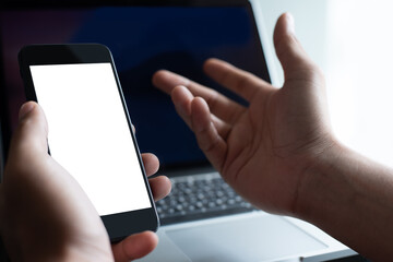 Mockup of man using mobile smart phone and working on laptop computer at office