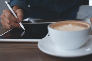 man using stylus pen on digital tablet working in coffee shop 