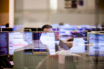 Business people working at desk on trading floor seen through glass window