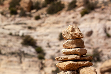 Fototapeta na wymiar An abstract image of stones stacked up in a tower shape. Stones are rough with detailed texture yet they balance in great harmony and make a pyramid shape. Useful demonstration for zen meditation.