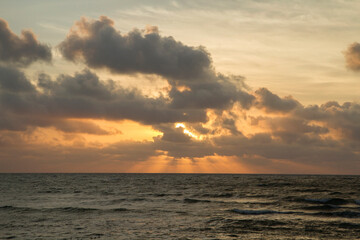 Vacations. Seascape. Dramatic view of the sky, clouds, ocean and sea waves at sunset. Beautiful golden colors.