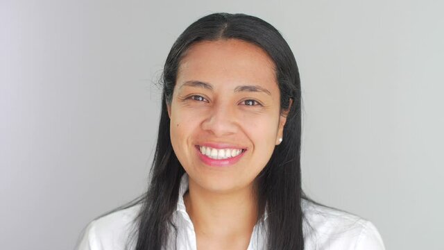 Close-up of a beautiful Latin American Hispanic young woman dressed in white, looking at camera, smiling