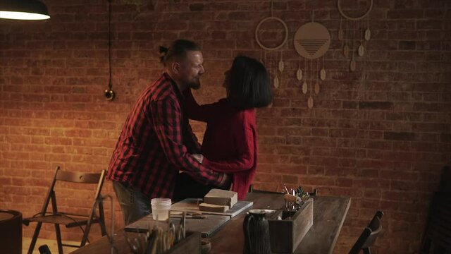 Spend Time Together. Guy Holds A Girl In His Arms Against A Brick Wall In A Pottery Workshop. First Date At The Master Class. Photo Session During Pottery Classes. Private Lessons With Ceramic.