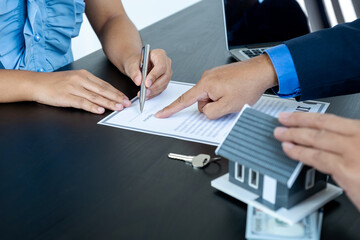 The buyer is signing a contract for business rental, mortgage purchase, or home insurance in front of a real estate agent