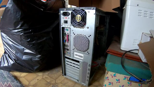 Old computer tower sitting next to garbage in a old home.