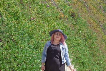 chubby mexican woman wearing summer hat in front of green plants wall