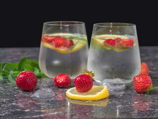 Strawberries and lemon slices on the background of two glasses with a cold drink. Selective focus.