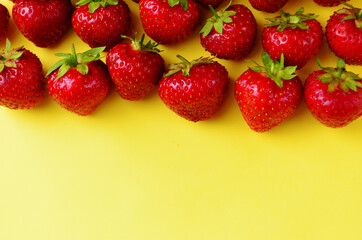 lots of red strawberry berries lined along the top edge on a yellow background kind of fresh