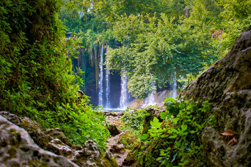 Waterfall in the rainforest, rocks and foliage in the foreground. Upper Duden waterfall in Turkey, Antalya