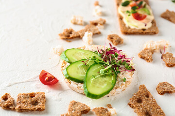 Tasty crispbread with cucumber and sprouts on white background