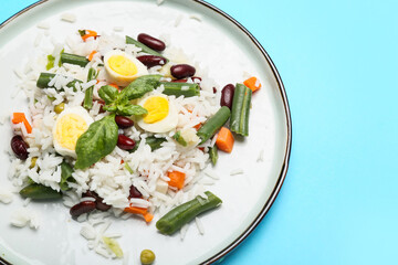 Plate with tasty rice, beans, egg and vegetables on color background
