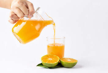 Hand pouring orange juice from jug with into glass on white background