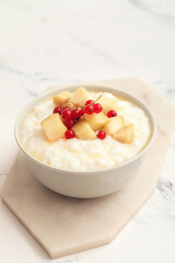 Bowl with boiled rice and fruits on table
