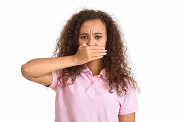 Young African-American woman covering her mouth on white background. Stop racism