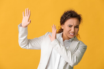 Scared African-American woman on color background. Stop racism