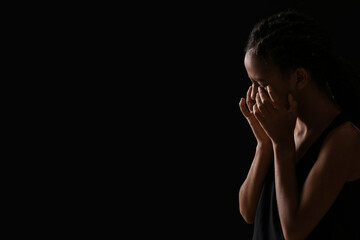 Sad African-American girl on dark background. Stop racism