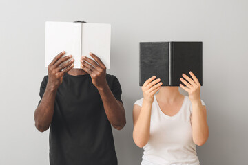 Caucasian woman and African-American man with books on grey background. Racism concept