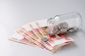 A glass jar with coins is on five-thousand-dollar bills, the concept of interest on deposits in...