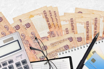 10 Indian rupees bills and calculator with glasses and pen. Tax payment concept or investment solutions. Financial planning or accountant paperwork