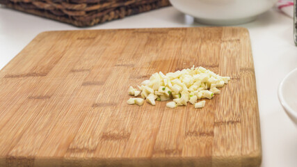 Chopped garlic on a wooden chopping board close up on a kitchen table