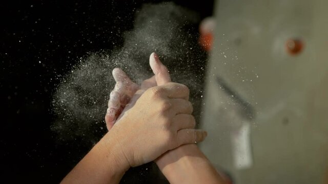 SLOW MOTION, CLOSE UP, DOF: Two female climbers shake hands after successfully climbing a difficult route. Unrecognizable women celebrate a good rock-climbing session at a new indoor training center.