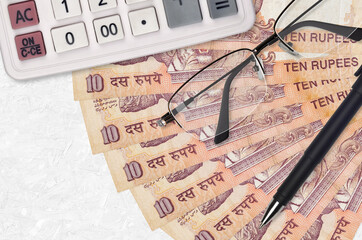 10 Indian rupees bills fan and calculator with glasses and pen. Business loan or tax payment season...