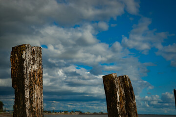 Two Old pier posts below cloudy sky.